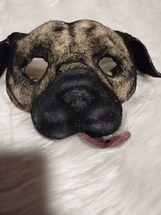 a close up of a dog mask on a white fur surface