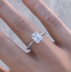 a woman's hand with a diamond ring on it and an emerald stone in the middle