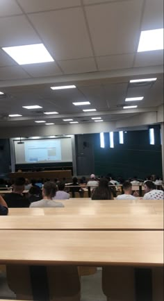 people are sitting at desks in front of a projector screen