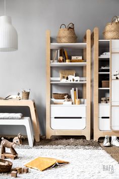 a living room with two white bookcases and toys on the floor in front of it