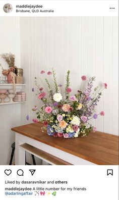 a bouquet of flowers sitting on top of a wooden table next to a shelf filled with knick knacks