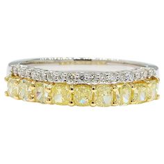 three rows of yellow and white diamonds on a gold plated ring, set against a white background