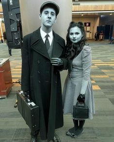 a man and woman standing next to each other in front of a wall with luggage