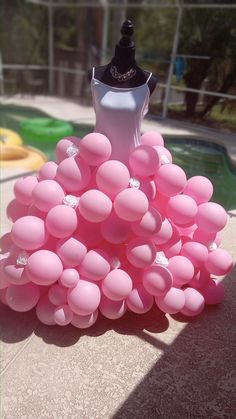 a dress made out of balloons sitting next to a pool