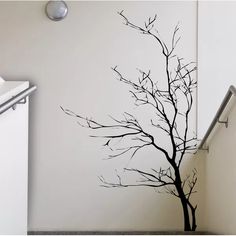 there is a black tree on the wall next to a white door and some stairs