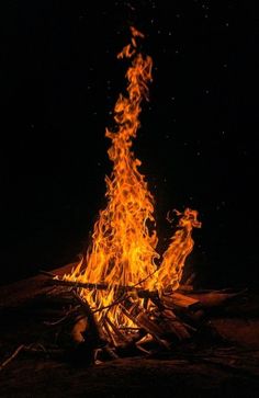 a bonfire is lit in the dark with bright orange flames coming out of it's sides