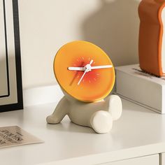 an orange clock sitting on top of a white table