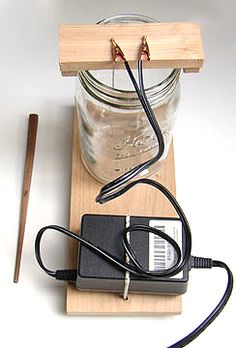 an electronic device is plugged into a mason jar on a wooden block with a pen