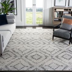 a living room with a couch, chair and rug on the floor in front of a window