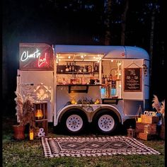 a food truck parked in the grass with lights on it's roof and decorations