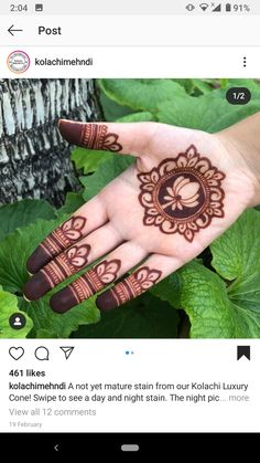 someones hand with henna tattoos on it and green leaves around the palm area