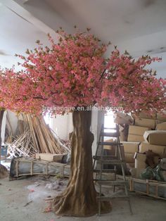 a tree with pink flowers is in the middle of a room filled with chairs and ladders