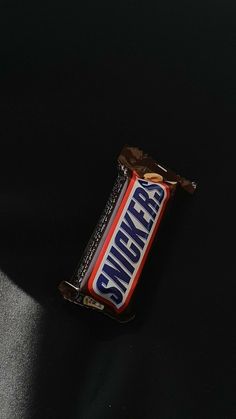 a bar of snickzer chocolate sitting on top of a black table next to a banana