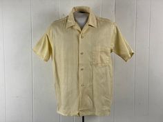 "Vintage 1960s Rockabilly shirt. Made of pale yellow cotton with beige micro stripes. Has a top button loop, button down front, horizontal button holes, straight cut hem and single chest pocket. Label reads: SEARS 100% COTTON U.S.A. Size medium.  Actual measurements are:  46\" at the chest  47\" at the waist  18\" shoulder seam to shoulder seam  28\" overall length   In excellent unused condition, New Old Stock." Yellow Retro Shirt With Buttons, Vintage Single-breasted Button-up Tops, Yellow Retro Top With Button Closure, Vintage Snap Button-up Tops, 1970s Button-up Top With Buttons, Rockabilly Shirts, Yellow Shirt, Yellow Shirts, Vintage Shirt