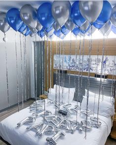 a bed topped with lots of blue and silver balloons