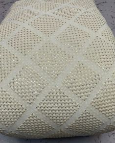 a close up of a white pillow on a floor with holes in the fabric that is covering it