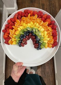 a white plate topped with sliced fruit and a rainbow shaped cut in half on top of a wooden table