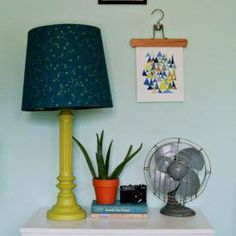 a table with a lamp, fan and pictures on the wall