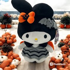 a hello kitty stuffed animal surrounded by pumpkins