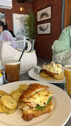 there is a sandwich and potato chips on the plate next to each other at this restaurant