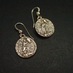 two silver earrings with roman coins on them