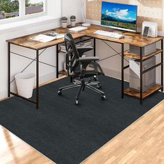 a computer desk with a monitor and keyboard on top of it in front of a window