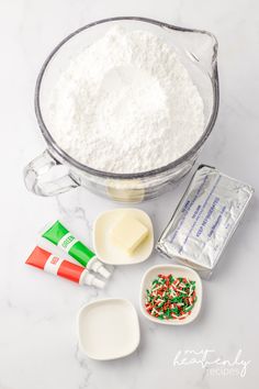 ingredients to make cake in a mixing bowl on a marble counter top, including flour, butter, sugar, and sprinkles