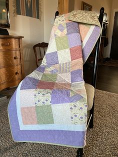 a bed with a quilt on top of it and a chair in front of it