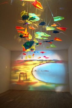 an art installation in a white room with multicolored objects hanging from the ceiling