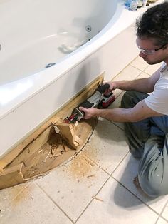 a man is working on the floor in front of a bathtub that's being built