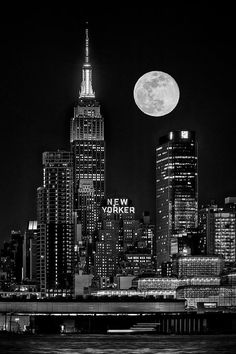 black and white photograph of the new york city skyline at night with full moon in background