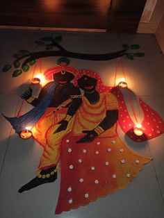 a painting on the ground with candles around it and two people holding each other's arms