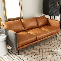 a brown leather couch sitting on top of a rug