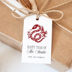 a gift wrapped in brown paper with a red snake on it and the tag says happy year of the snake