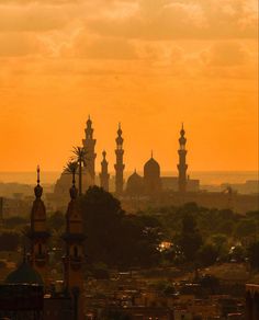 the sun is setting over an old city with many spires and buildings in the foreground