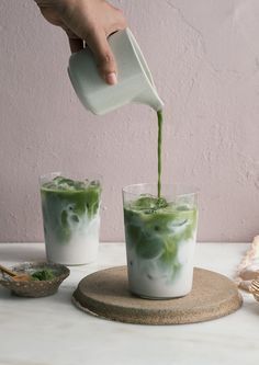 someone pouring green liquid into two glasses