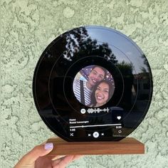 someone is holding up a clock with an image of two people in the circle on it