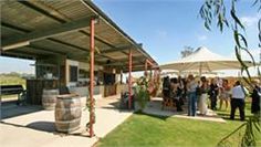 a group of people standing under an awning next to a building with barrels on it