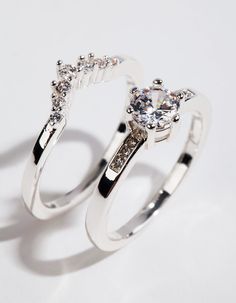 two silver rings with diamonds on them sitting side - by - side against a white background