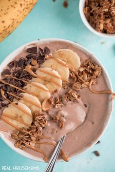 a bowl filled with chocolate and bananas on top of a blue table next to a banana peel