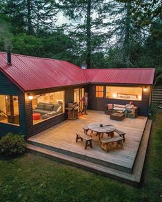 a small cabin in the woods with a deck and picnic table