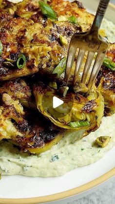 a fork is stuck into some food on a plate with mashed potatoes and green onions