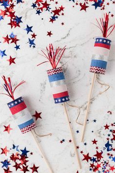 three red, white and blue fireworksticks on a marble surface surrounded by stars