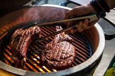 steak being grilled on the grill with tongs in it's mouth and someone holding chopsticks