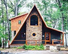 a small cabin in the woods surrounded by trees and rocks, with a porch on each side