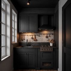 a kitchen with black cabinets and wooden floors