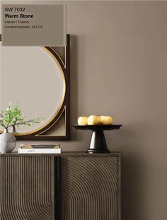 a vase with flowers on top of a wooden cabinet in front of a wall mounted mirror