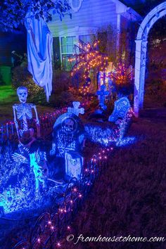 halloween decorations in front of a house with skeletons on the lawn and lights around them