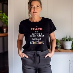 a woman standing with her hands on her hips wearing a black t - shirt that says teach