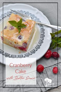 a white plate topped with a piece of cake next to raspberries and mint